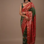 Bottle Green Saree In Silk With Multi Colored Patola And Foil Print And Contrasting Red Border